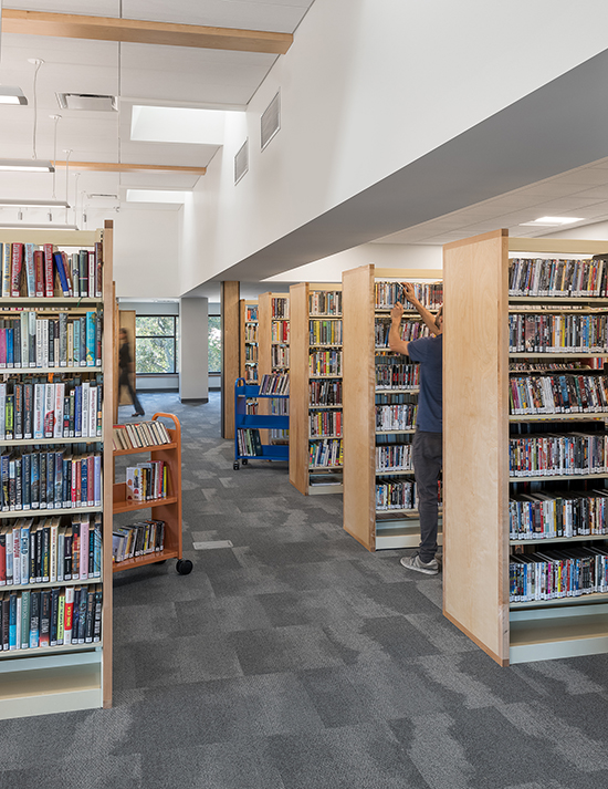 Pierson Library interior with volunteer shelving books in the adult non-fiction area